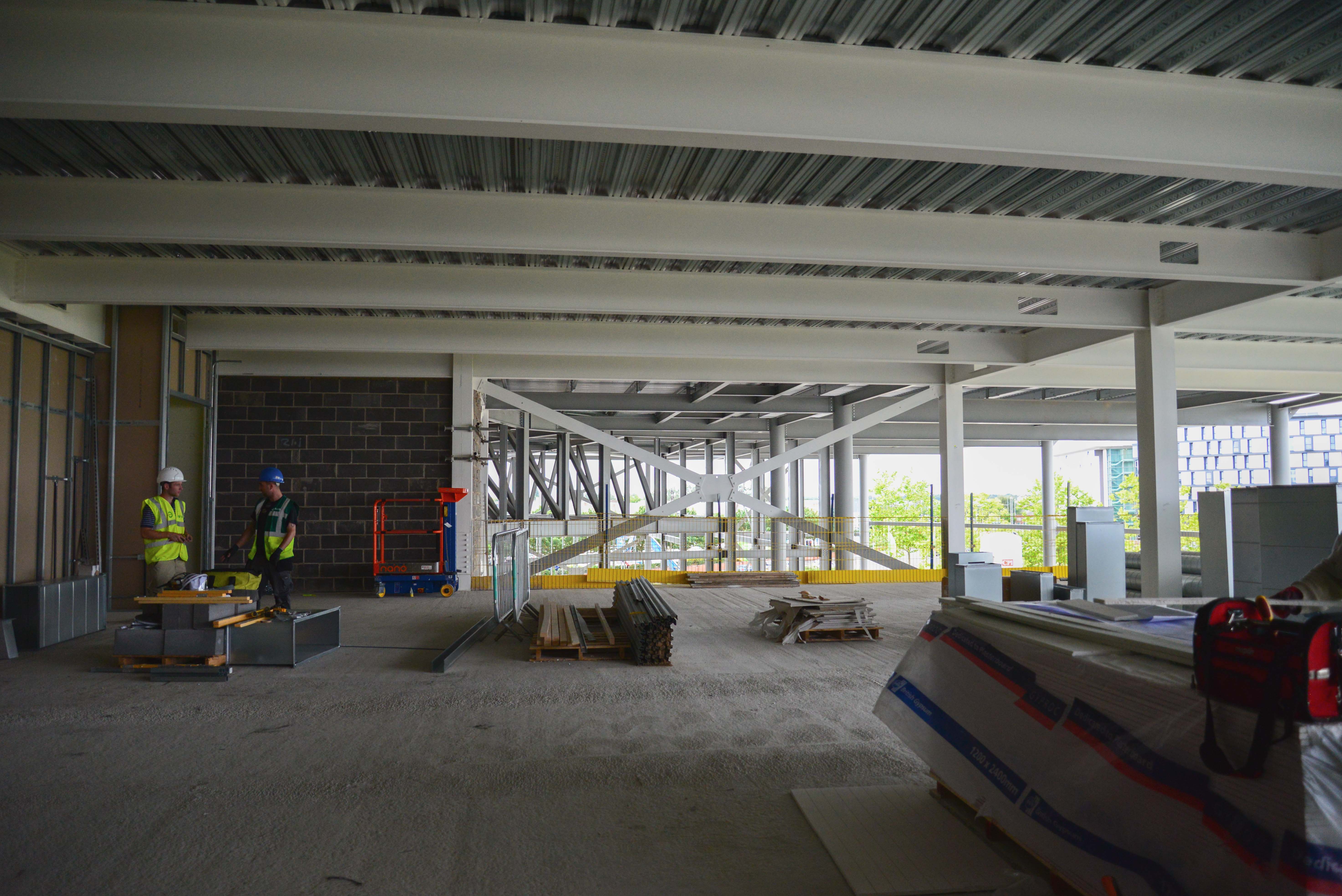 Image of a large room in construction. The walls and ceiling are bare