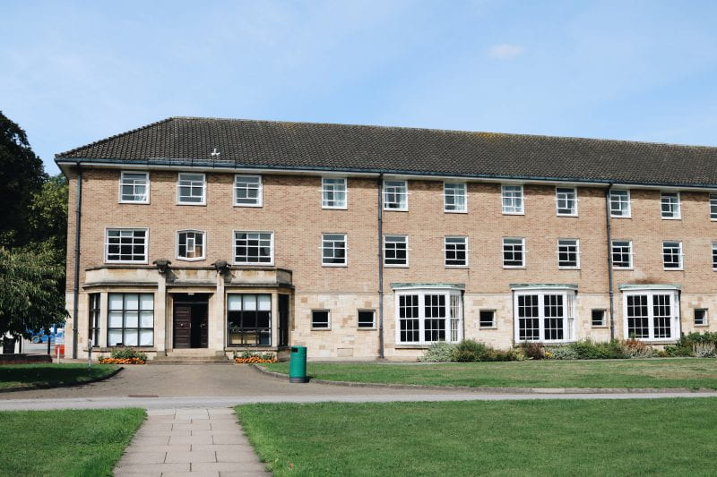 Image of a long 3 storied building built of stone and light coloured brick
