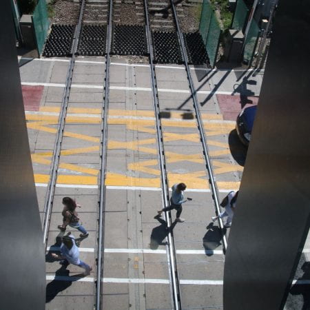 Image of some people walking across a railway crossing from above