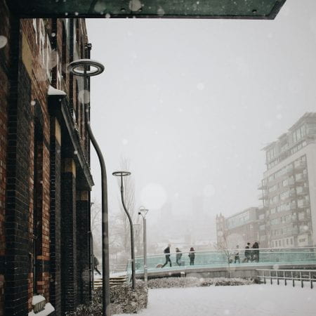 Image of a snowy bridge with people walking past