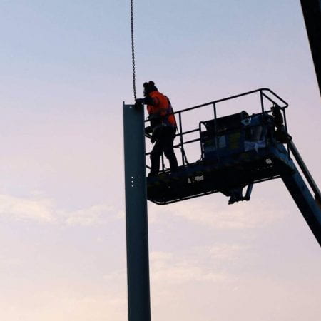 Image of a worker on a crane near steel frame works