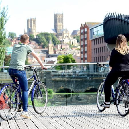 Image of cyclists on a bridge. A cathedral is in the background.