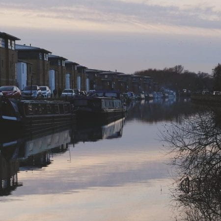 Image of a canal at sunset with buildings at either side of the canal.