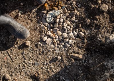 A column of pebbles and stones can be seen installed in the ground, roughly circular in shape.