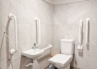 A disabled toilet under construction, infrastructure is white and the walls are light grey.