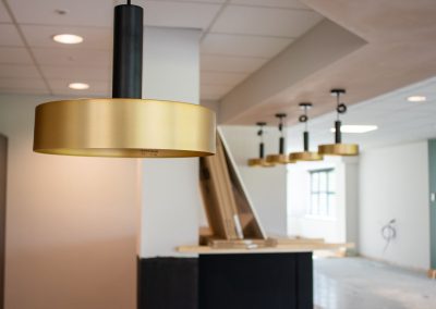 A brass light fitting hangs down from the ceiling with other fittings beyond