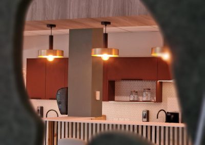 Brass pendant lights with orange vintage style light bulbs hang over a wooden counter. Red cupboards line the back wall.