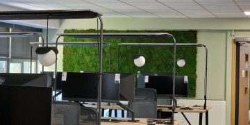 Workstations with curved screens and a moss wall.